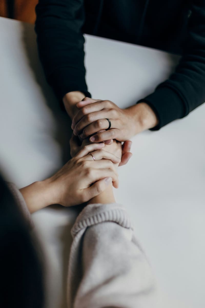 Two people holding hands, a gesture of comfort and support.