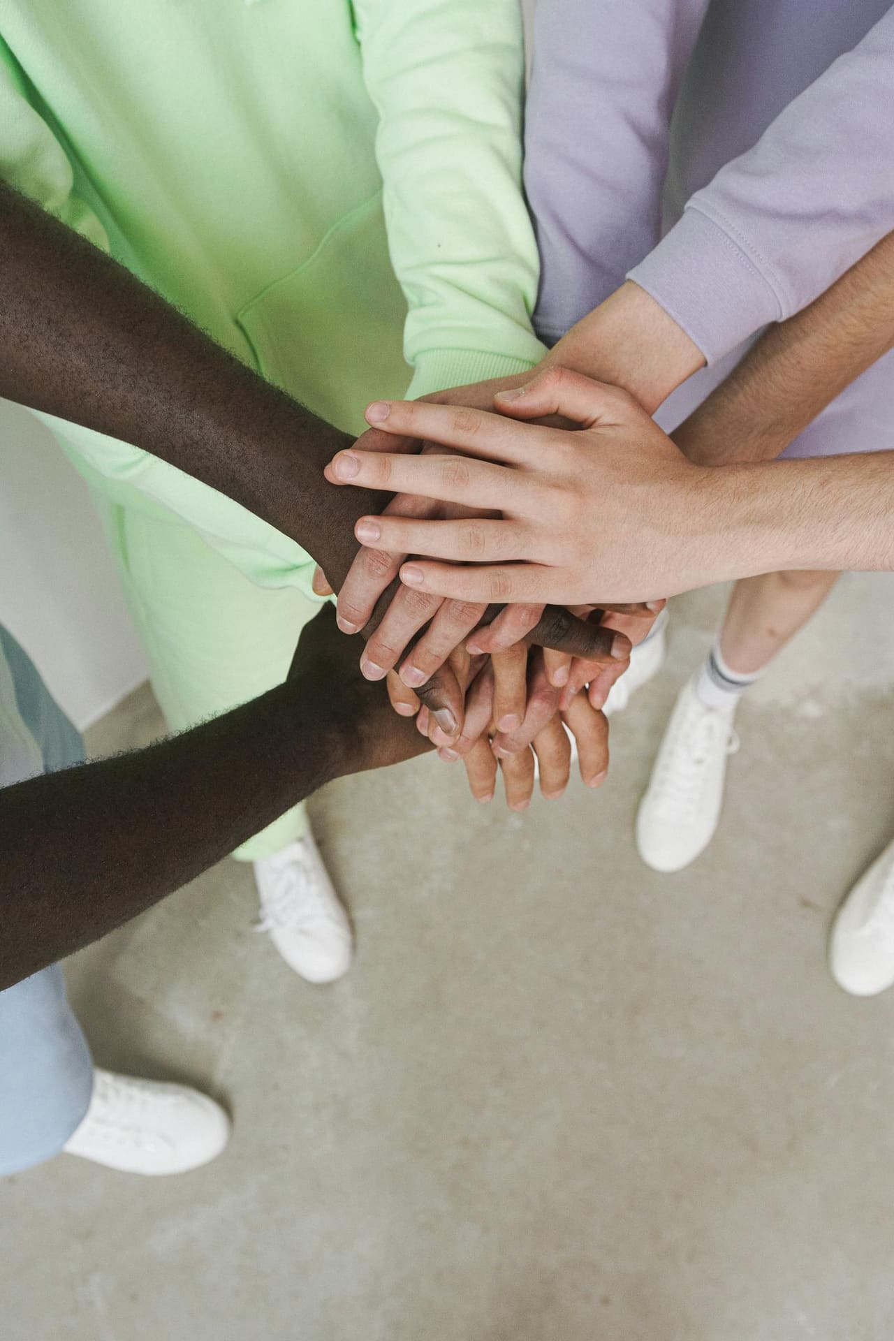 A group of hands stacked together in a gesture of unity and support.